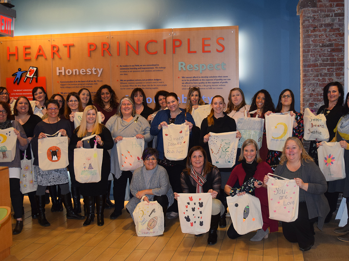 Caring Bright Horizons employees hold up drawings